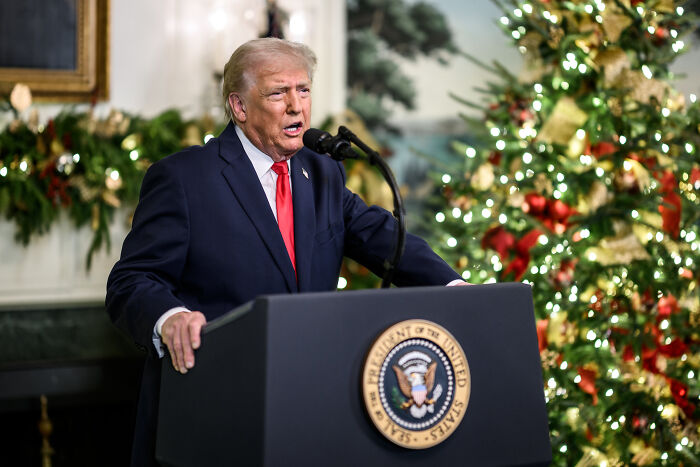 Former president speaking at a podium with presidential seal during a holiday event in a decorated room, Trump Kennedy Center topic.