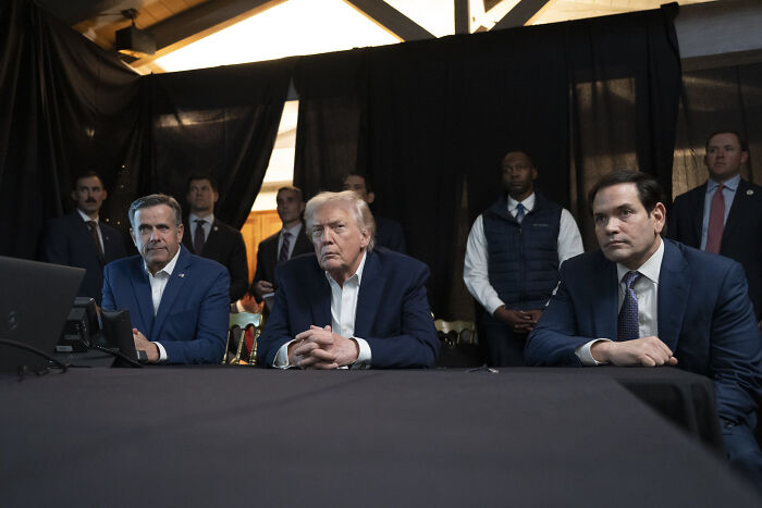 Group of politicians including Trump seated at table during a discussion on Venezuela operation involving MTG and Democrats.