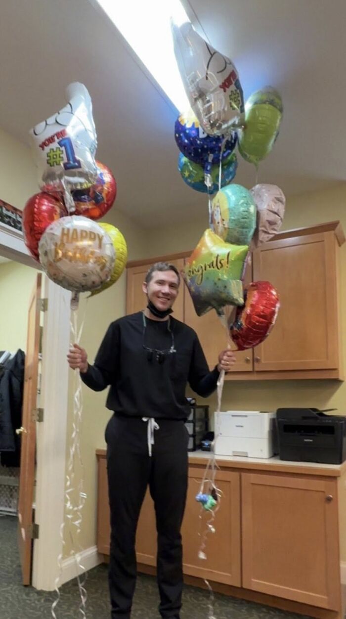 Smiling man holding colorful celebration balloons in an office, Slain Ohio Couple