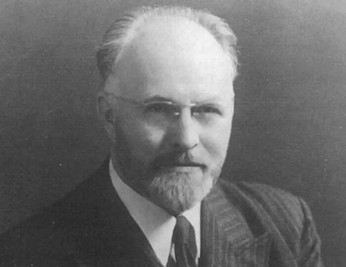 Black and white portrait of a man in a suit and glasses, related to Elon Musk's grandfather and radical anti-democracy plan.