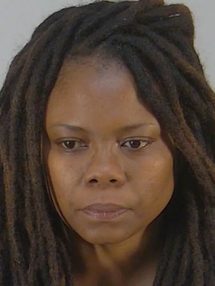 Woman with long dreadlocks looking solemn in a close-up portrait related to child a***e case and homicide sentencing.