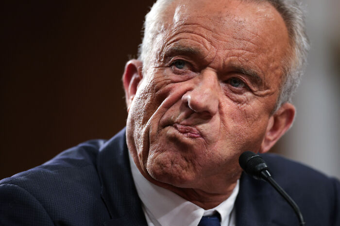 Man in a suit at a press conference with a serious expression as RFK Jr.&rsquo;s ringtone interrupts the event