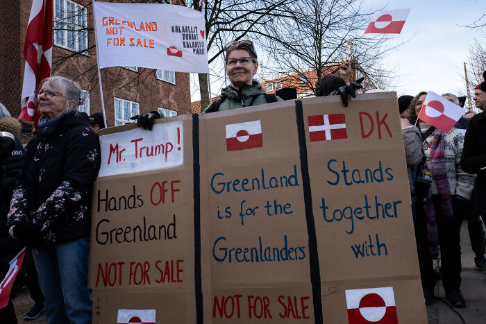 Protesters holding signs against Trump&rsquo;s Greenland purchase, emphasizing Greenland is not for sale and its importance.