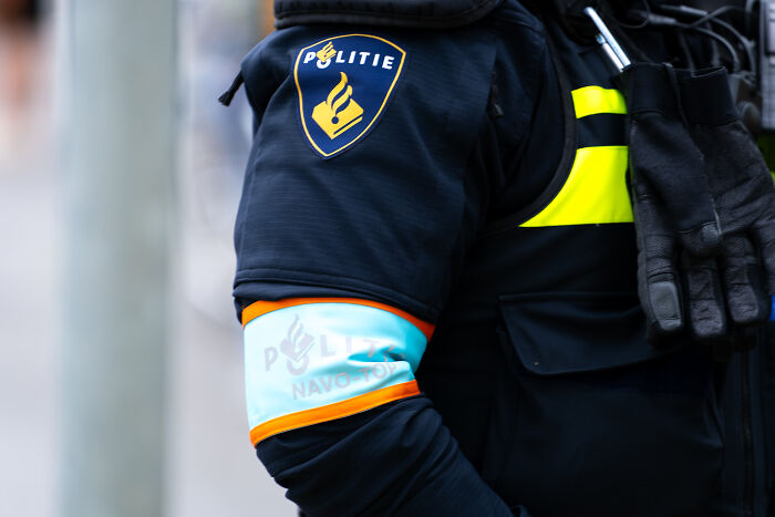 Police officer in uniform with Politie patch and reflective armband at scene, linked to honour-motivated homicide case