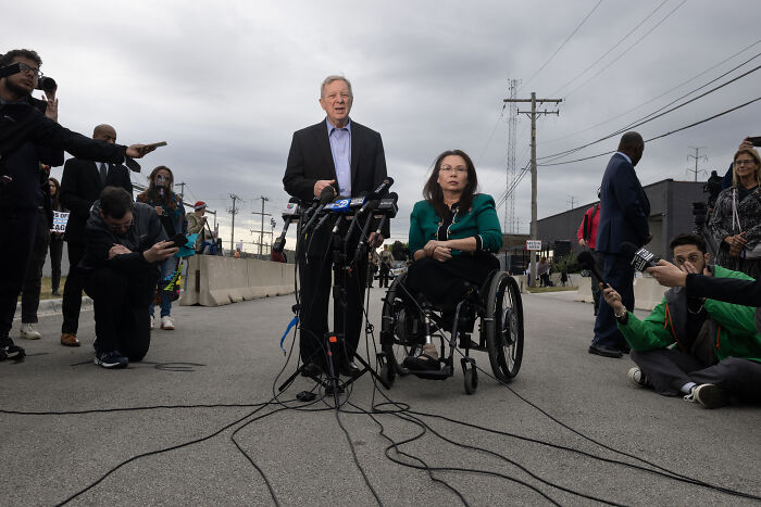 Politician speaking at outdoor press event next to a woman in a wheelchair amid controversy involving JD Vance and combat veteran.