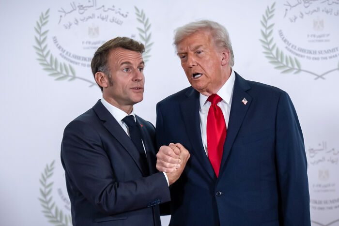 Donald Trump and Emmanuel Macron shaking hands at Davos ceremony urging world leaders to endorse Board of Peace.