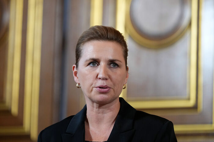 Greenland Prime Minister in a formal setting responding firmly with wood-paneled background and gold trim visible.