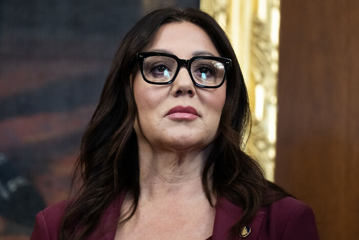 Woman wearing glasses and a burgundy blazer at a formal event, related to Trump labor secretary adult club trip probe.