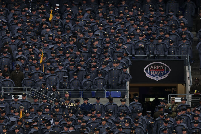Large crowd of military cadets in uniform at Army Navy football game showing support and holding a beat Navy sign.