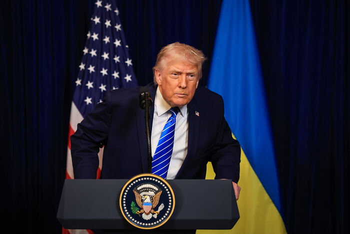 Former President Trump at a podium with American and Ukrainian flags, related to health issues and compression socks.