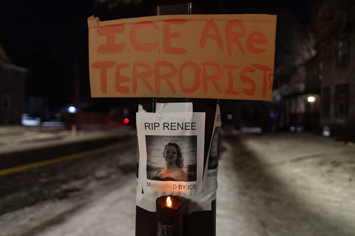 Protest sign reading ICE are terrorists above a memorial with a photo of a woman who died, highlighting ICE-related tragedy.