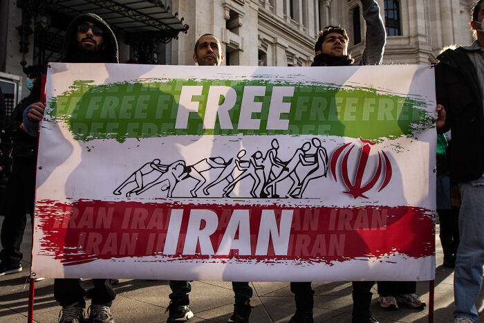 Protesters holding a Free Iran banner with Iran&rsquo;s flag colors amid discussions of Trump&rsquo;s strong options in Iran.