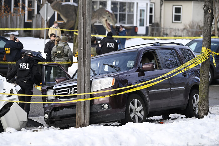 FBI agents investigate a crime scene involving a SUV and police tape after fatal shooting linked to ICE incident.