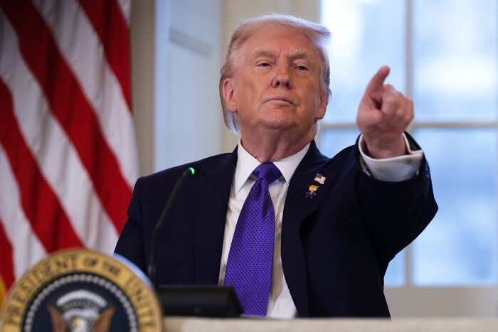 Former President Donald Trump speaking at a podium with the American flag behind him during a formal event.