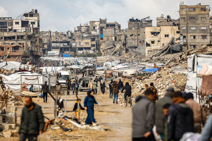 Damaged buildings and residents in a devastated area, related to Putin&rsquo;s Gaza peace board discussions.