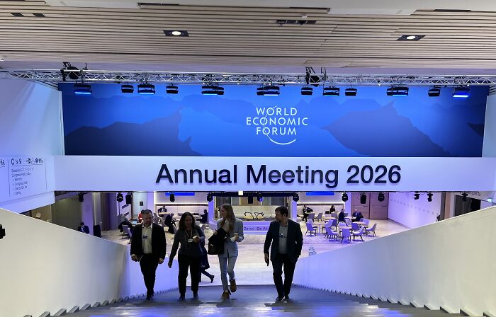 Attendees walking at the World Economic Forum Annual Meeting 2026 in Davos, promoting board of peace endorsement.