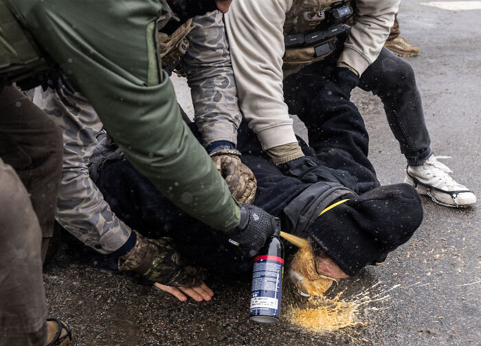 Alex Pretti clashing with federal agents, restrained on the ground with spray used during the confrontation.