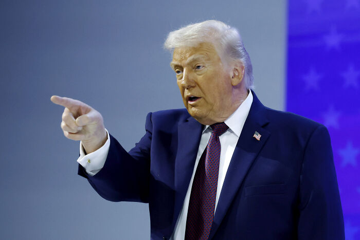 Former President Donald Trump in a dark suit pointing during a speech, related to JB Pritzker and Border Patrol news.