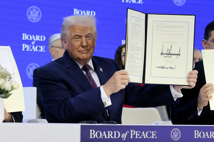 Donald Trump holding signed document at a Board of Peace ceremony, shunned by all major allies during key event.