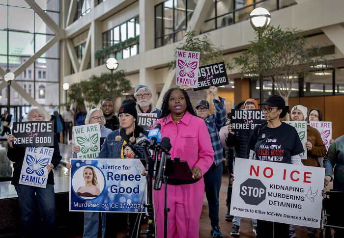 Protesters gather indoors holding signs calling for justice amid White House sharing modified Minnesota church protester image.