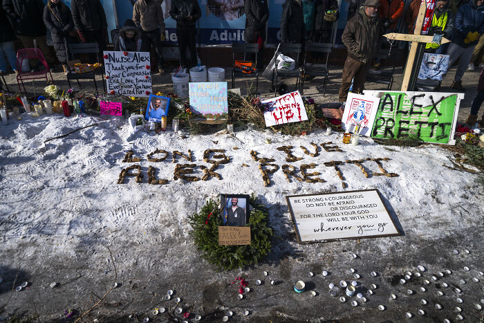 Memorial for Alex Pretti on snow with signs and candles as NRA and Americans call out MAGA 2nd Amendment hypocrisy.