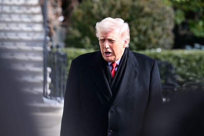 Donald Trump outdoors in a black coat reacting to the shooting of Alex Pretti, capturing viral moment expressions.