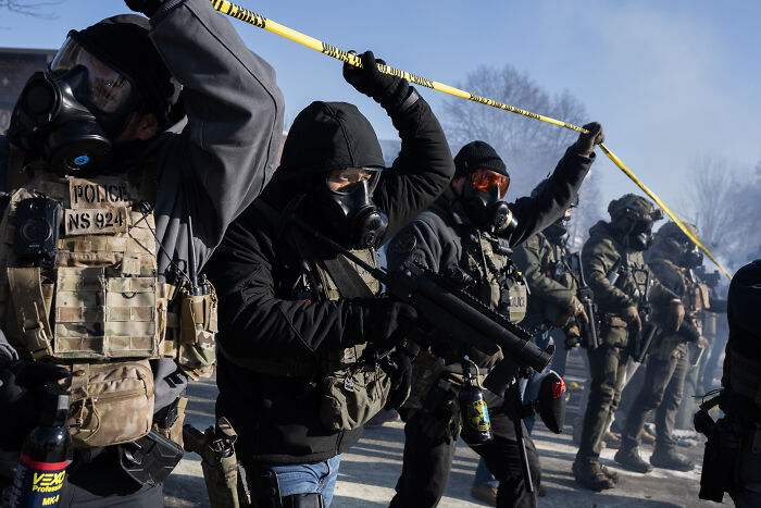 Federal agents in tactical gear and gas masks hold a police line during a confrontation days before Alex Pretti fatal shooting.