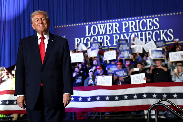 Donald Trump at rally in front of crowd holding signs about lower prices and gas prices fact-checked during speech.
