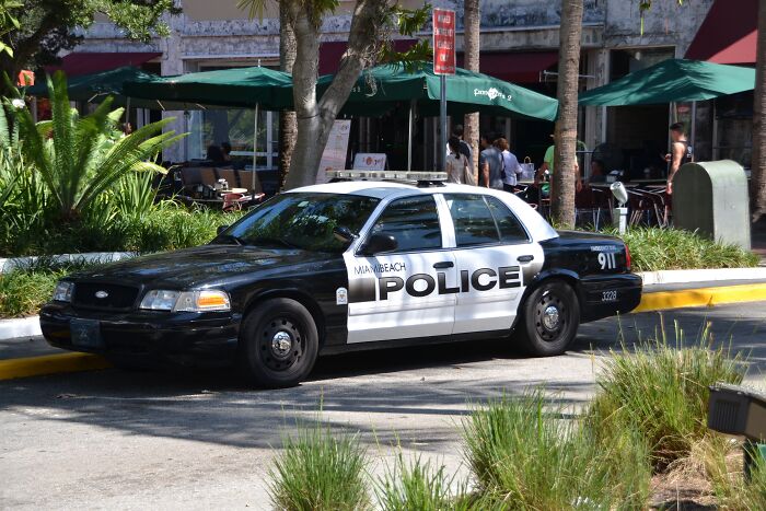 Miami Beach police car parked near outdoor cafe, linked to free-speech controversy involving Facebook comment inquiry.