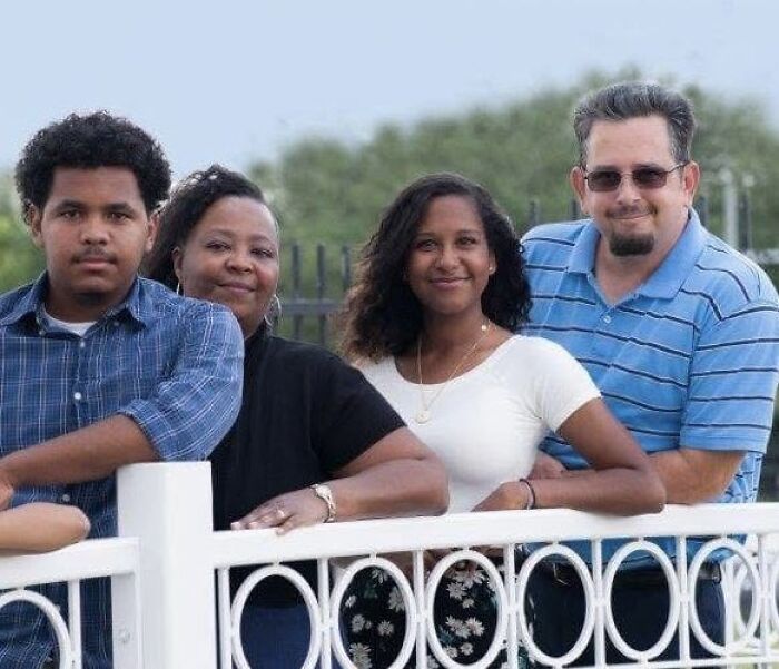Family standing together outdoors by a white fence, representing the couple that adopted a 7-year-old daughter in Texas case.