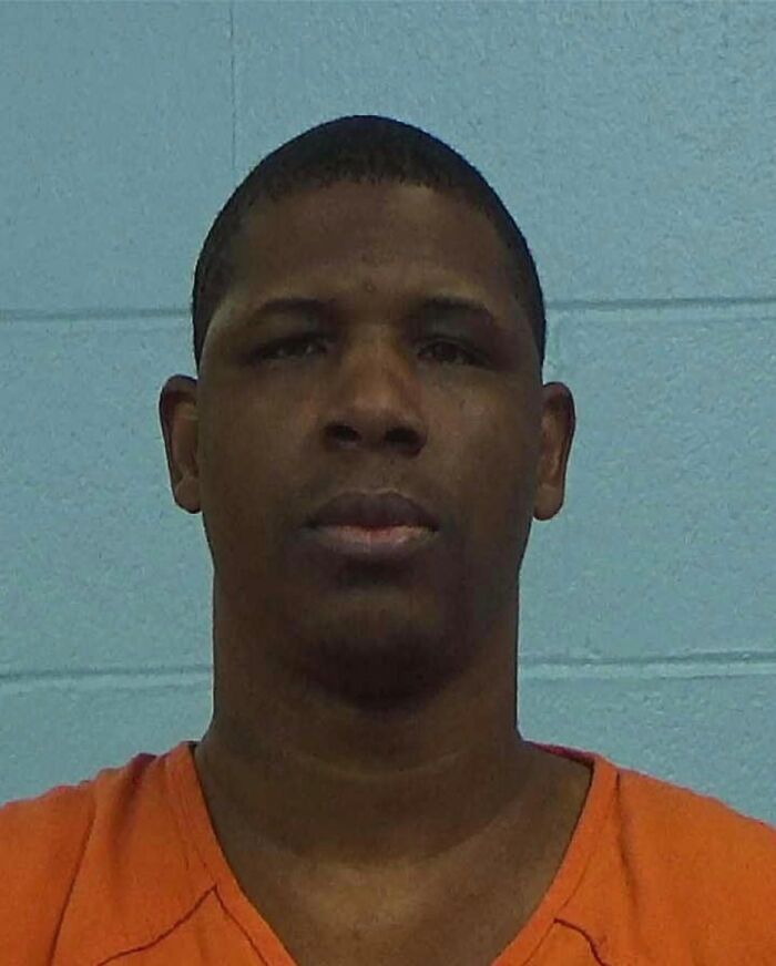 Mugshot of a man in an orange shirt linked to Texas man allegedly crosses state to slay couple case.