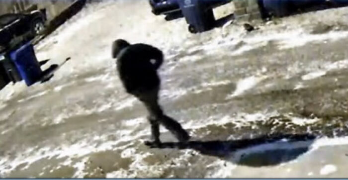 Surveillance image of lone figure walking in snowy driveway near trash bins, related to slain Ohio couple case