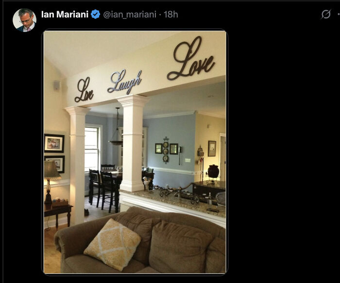 Interior view of a living room with decorative wall signs spelling Love, Laugh, and Love above columns.