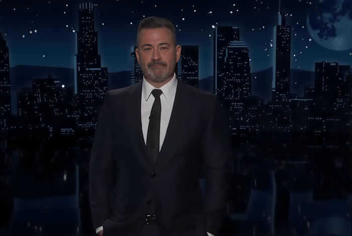 Jimmy Kimmel standing in front of a nighttime cityscape, delivering an emotional speech fighting back tears.