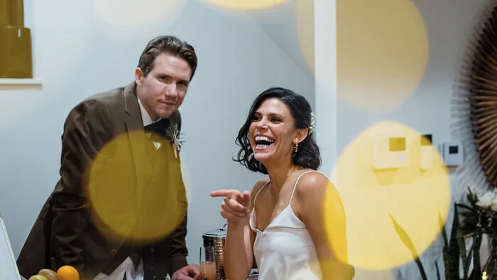 Slain Ohio couple laughing at a wedding reception with warm bokeh lights in the foreground