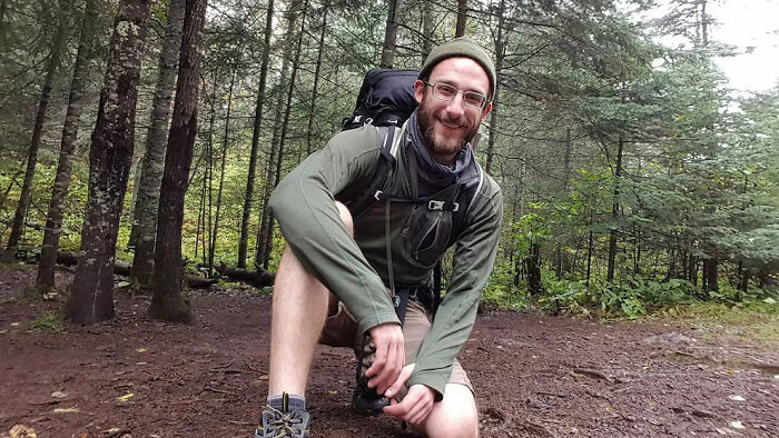 Man in outdoor gear kneeling on forest trail, highlighting celebrities voicing outrage at ICE after Alex Pretti shooting.