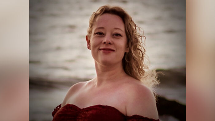Woman with curly hair smiling at the beach during sunset, related to Kristi Noem goes bonkers reporter incident.