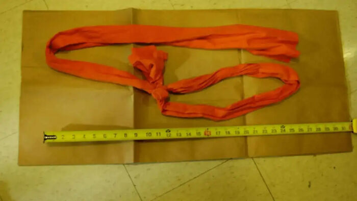 Resuscitation efforts equipment including an orange cloth strap and measuring tape on a floor surface in a cell setting.