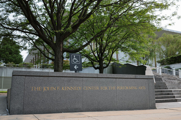 The Kennedy Center entrance with trees and a sign indicating wheelchair accessibility for repairs closure.
