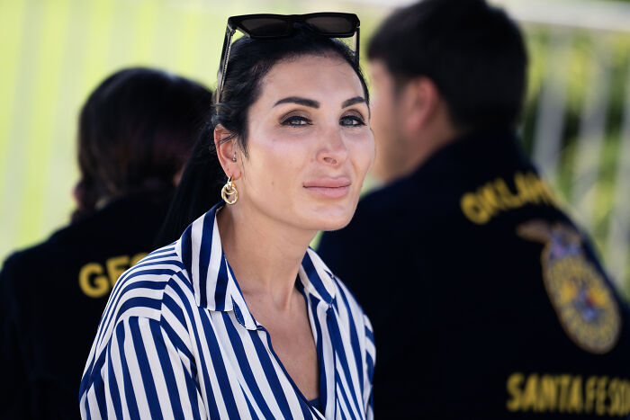 Laura Loomer outdoors wearing striped shirt and sunglasses, amid controversy over Super Bowl posts.