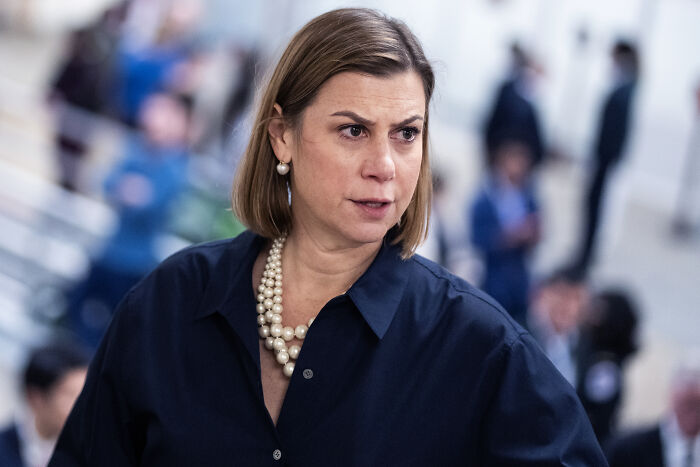 Woman in a navy shirt and pearl necklace at a public event, related to grand jury blocking DOJ charges military video.