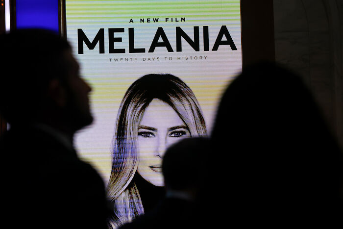 Melania Trump documentary poster with silhouettes of people in foreground at a film event or premiere.