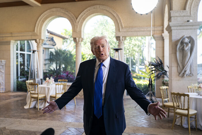 Donald Trump speaking with arms open in a formal setting, discussing the Kennedy Center closure for repairs.