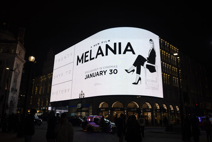 Large illuminated billboard at night promoting the Melania documentary releasing January 30 in cinemas.