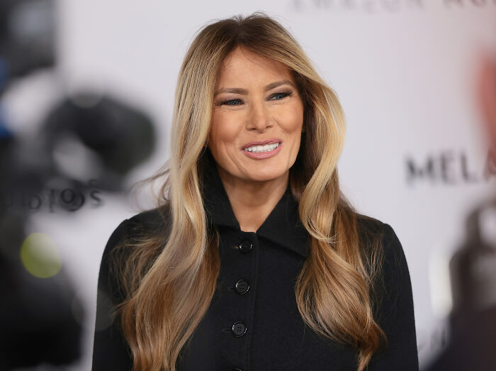 Melania Trump at a documentary event, smiling with long blonde hair, highlighting Melania Trump documentary box office success.