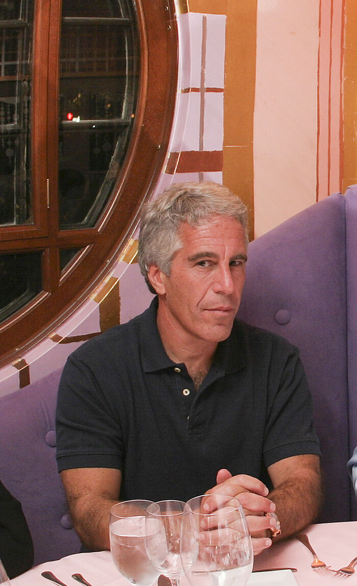 Man with gray hair in a black polo shirt seated at a table with glasses, relating to vanished Mexican model claims in Epstein files