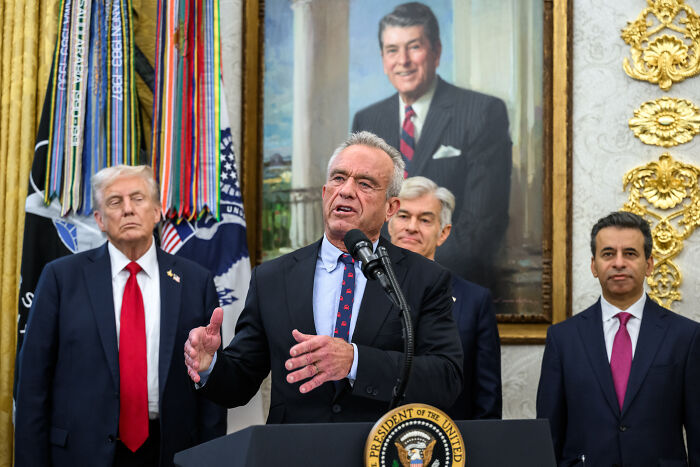 Man speaking at a podium with presidential seal and portrait in the background, related to Mike Tyson Super Bowl MAHA ad news.