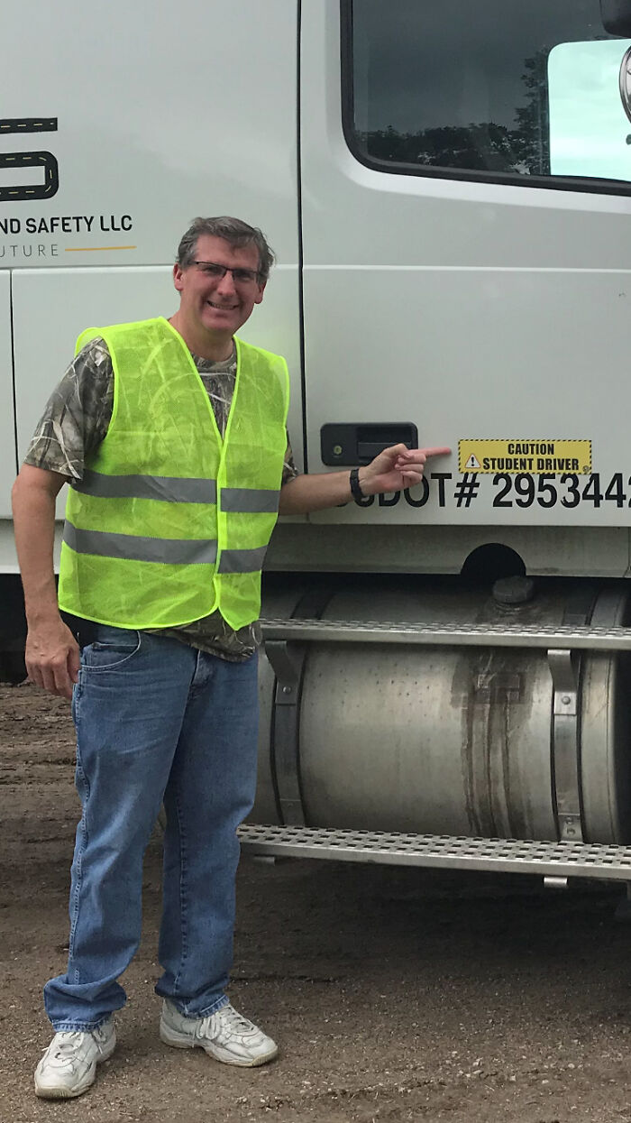 Man in reflective vest standing and pointing at truck decal, related to Minnesota gubernatorial candidate halting campaign after tragedy.