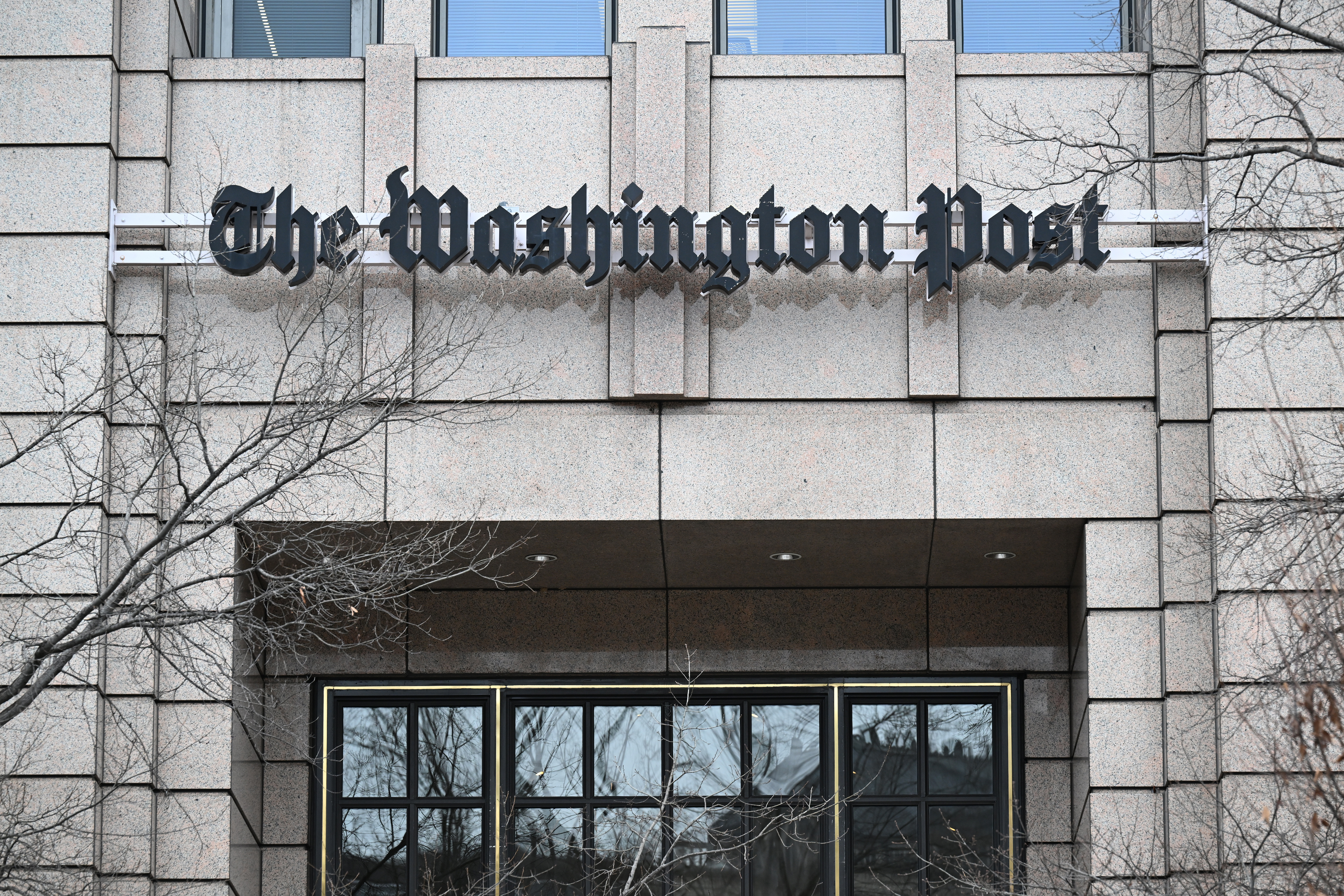 The Washington Post building exterior with logo amid controversy involving Jeff Bezos and journalist layoffs.
