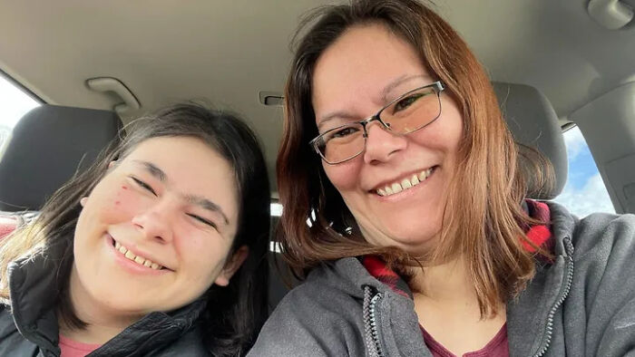 Two women smiling together inside a car, representing families honoring children lost in Canada school attack.